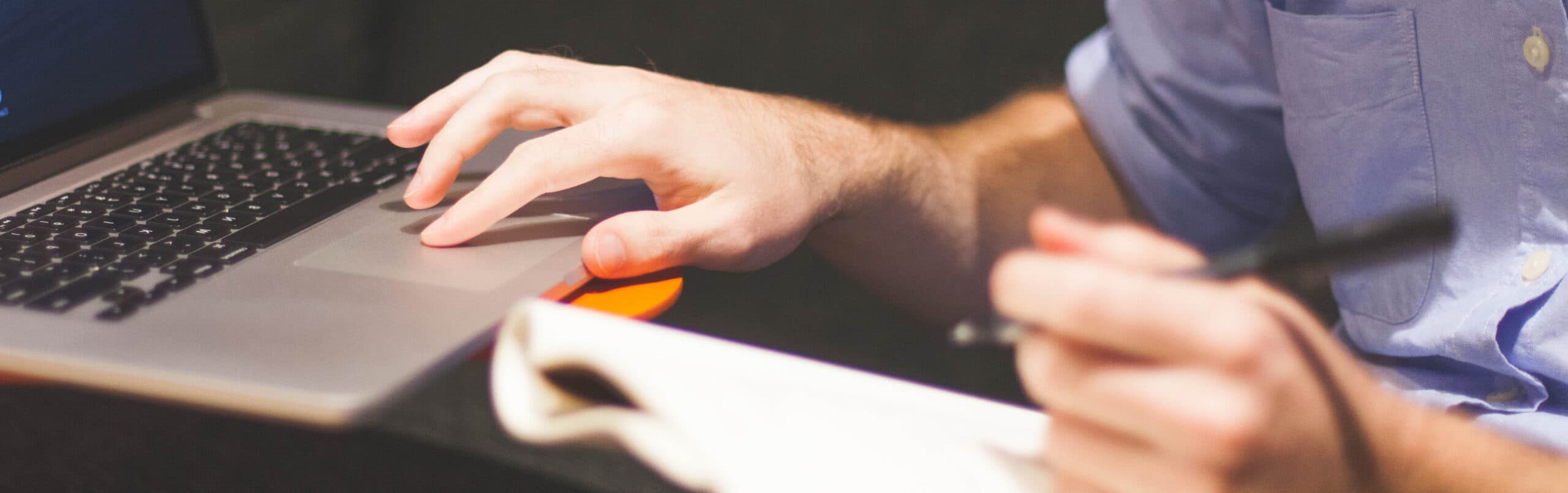 Man using a laptop and taking notes