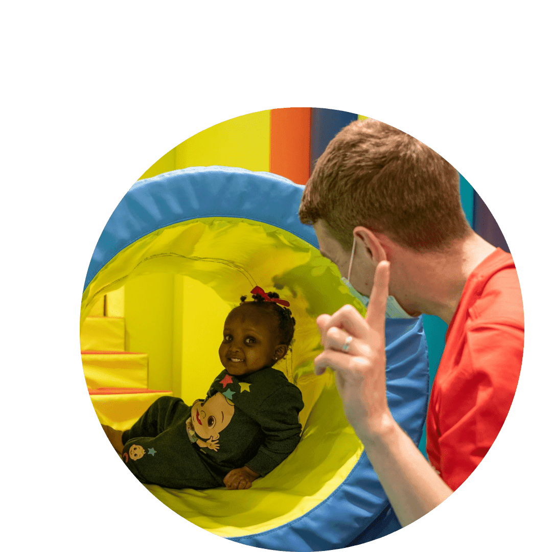 a little girl playing in a plastic tunnel