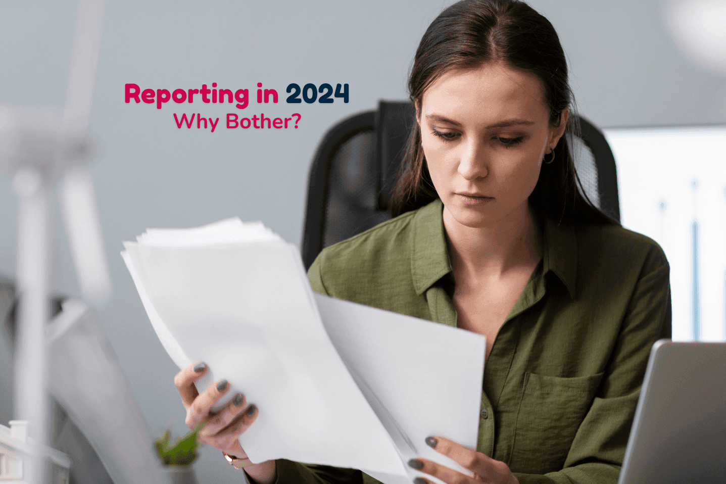 A woman in smart clothing holds A4 papers at her desk.