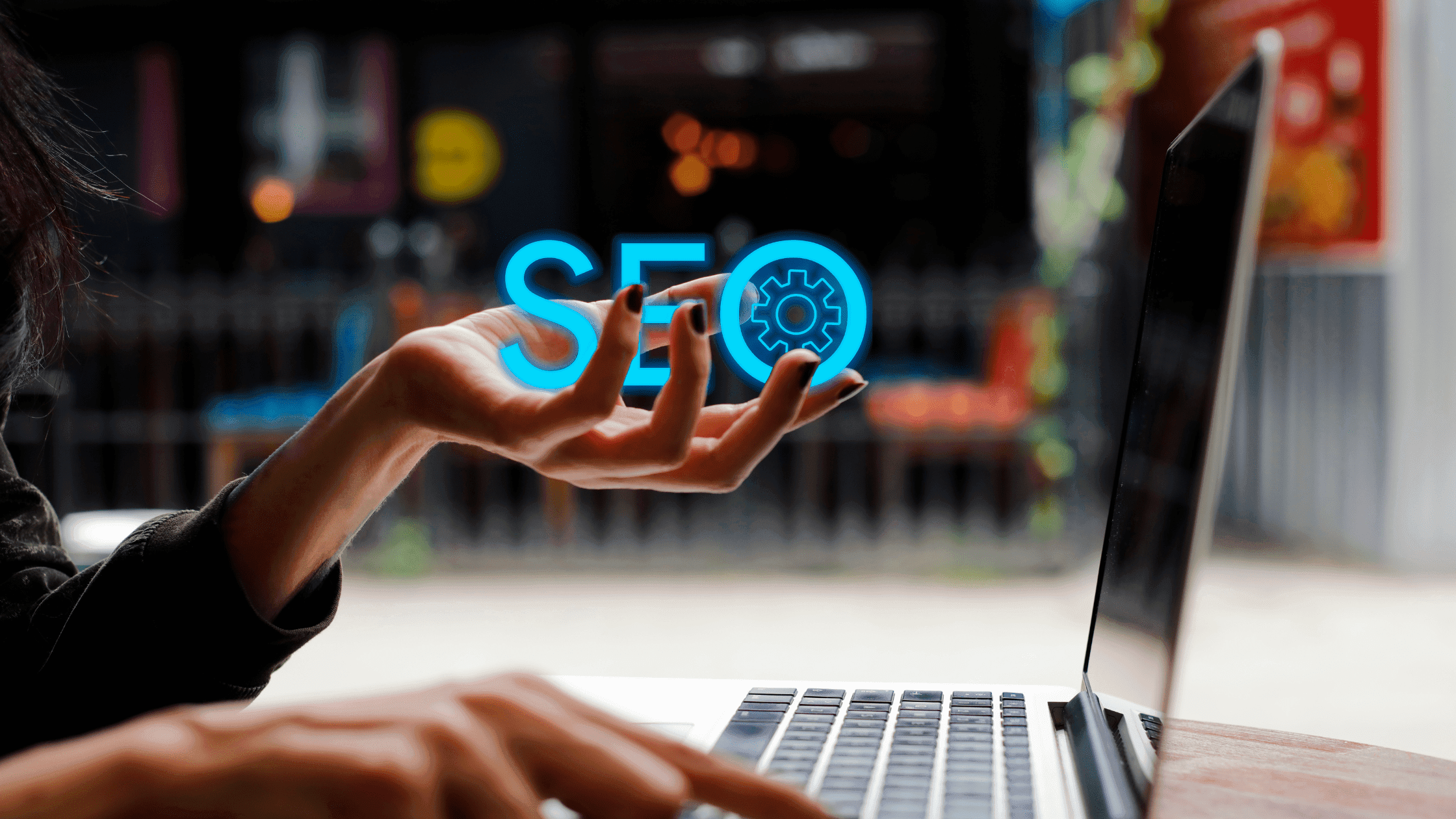 SEO text in left hand facing a laptop