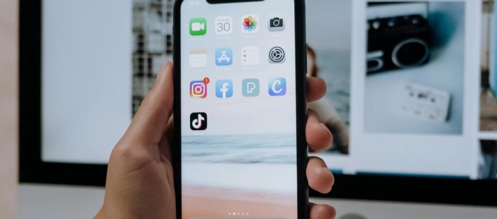 A hand holds a smartphone showing the Instagram and TikTok apps.