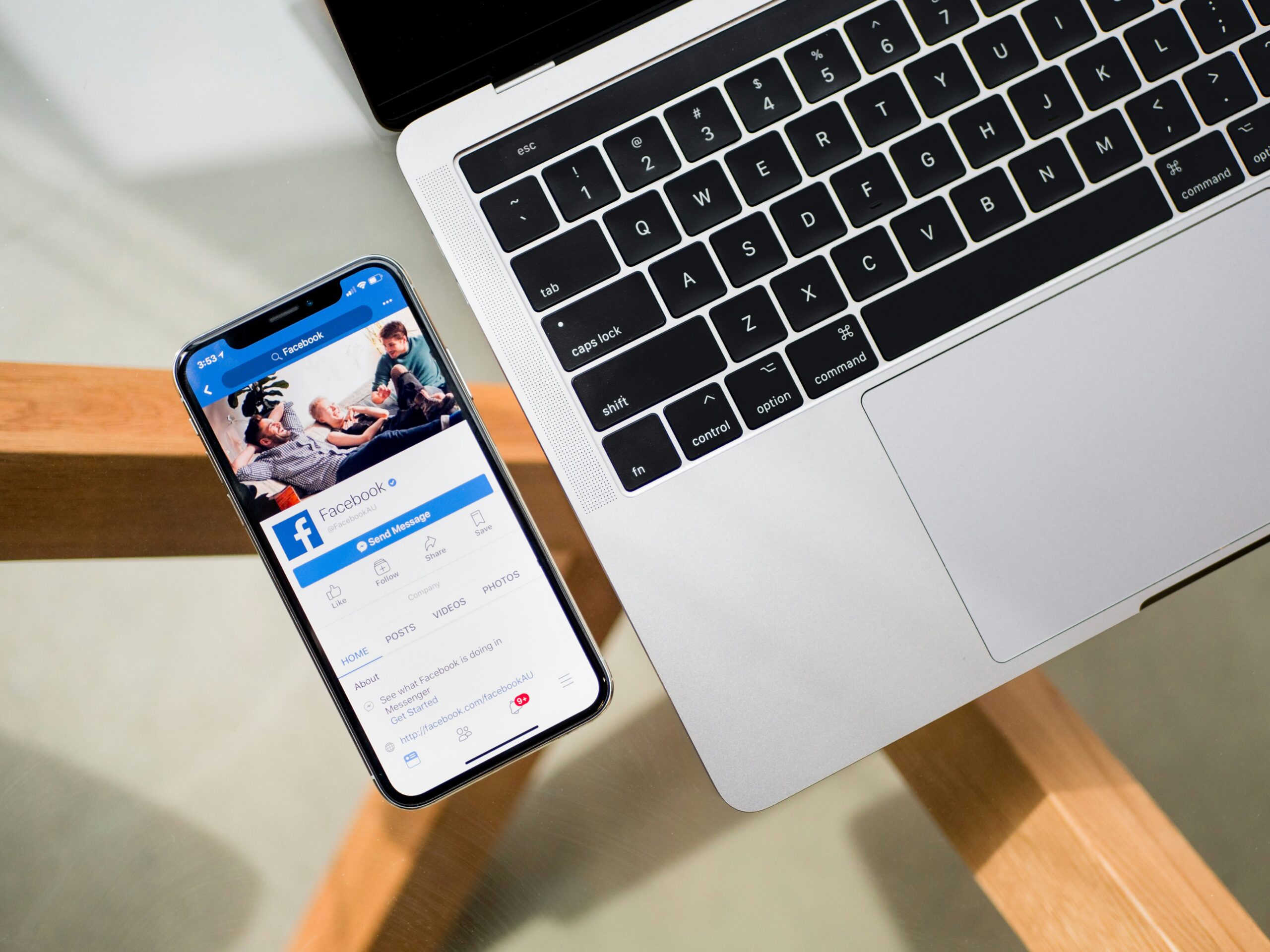 An open Facebook app on a phone next to a computer